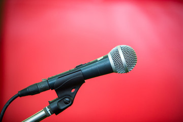 microphone in red background or conference room soft and blur style for background.Microphone over the Abstract blurred photo of conference hall or seminar room background.