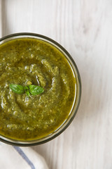 Basil pesto on white wooden background, top view. Flat lay, overhead, from above.