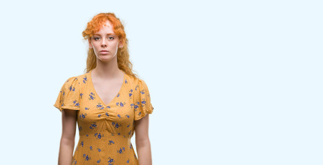 Young redhead woman with serious expression on face. Simple and natural looking at the camera.