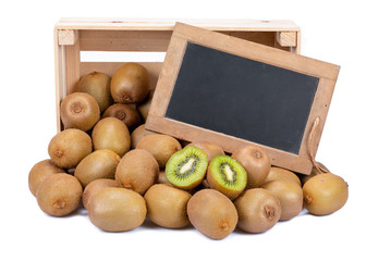 Wooden box filled with many ripe kiwi fruits and two half fruits and a old blank slate blackboard...