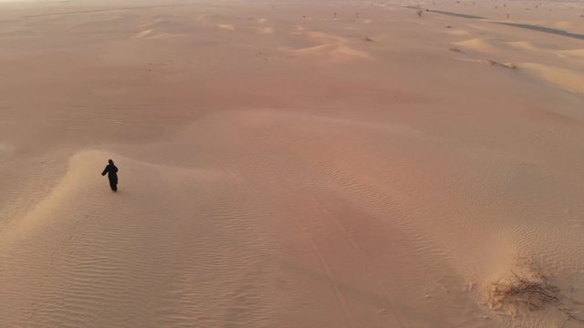 aerial view of a woman in abay walking in a desert