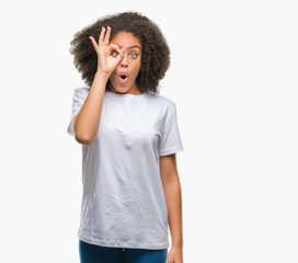 Young afro american woman over isolated background doing ok gesture shocked with surprised face, eye looking through fingers. Unbelieving expression.