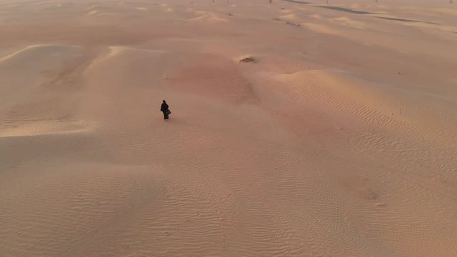 aerial view of a woman in abay walking in a desert