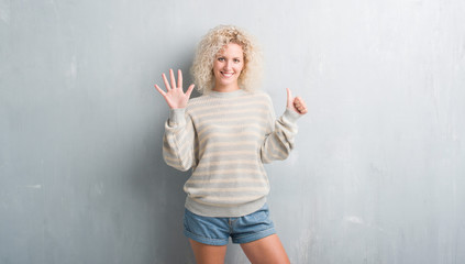 Young blonde woman with curly hair over grunge grey background showing and pointing up with fingers number six while smiling confident and happy.