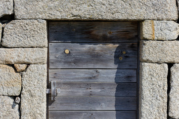 Puerta antigua de madera de roble en pared de piedra. Construcción tradicional en Vilar de Perdizes, Montalegre. Portugal.