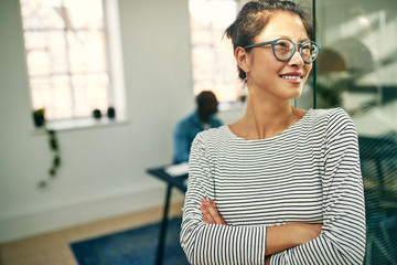 Smiling Asian businesswoman standing with her arms crossed at wo