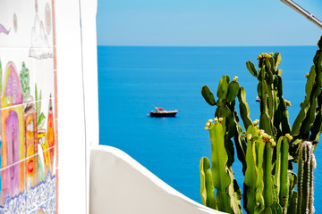 Vista del mar mediterráneo en las costas de Positano con un verde cactus de flores amarillas y una pared de mosaicos de colores. El mar azul en un día soleado de fondo. 