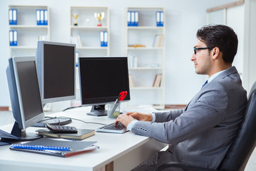 Businessman sitting in front of many screens