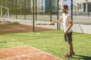 portrait of young man on the summer campus school tennis court