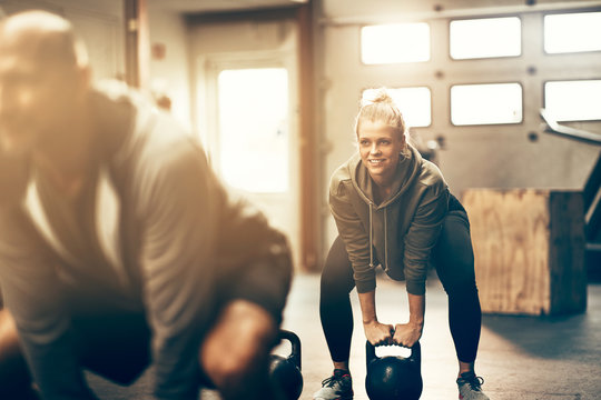 Smiling young woman lifting dumbbells during a gym exercise clas