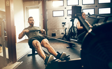 Fit man exercising on a rowing machine at the gym