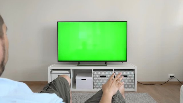 Watching tv with green screen at home interior. Changing channels on television