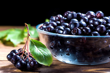 Aronia melanocarpa or black chokeberry in glass bowl on wooden table.Herbalism