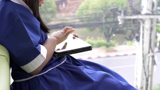 Asian little pupil playing writing on smartphone at the cafe