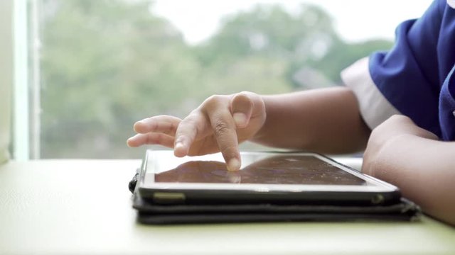 Asian little pupil playing writing on smartphone at the cafe