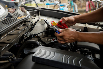 Engine engineer is replacing car battery because car battery is depleted. concept car maintenance.Selective focus charging car with electricity trough cables