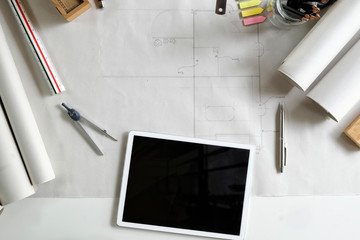 Workspace with blank screen tablet, pencil, architectural drawing paper for construction