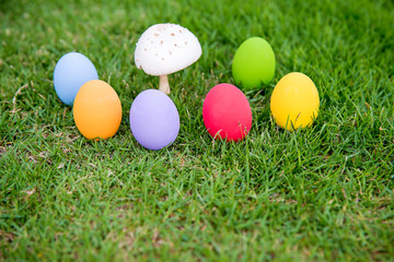 Fototapeta na wymiar Colorful easter eggs under the white mushroom on the green garden yard. symbol of easter's day festival. festive wallpaper. image for background, wallpaper,article,illustration and copy space.
