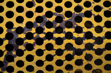 Closeup abstract yellow metal grill with holes pattern 