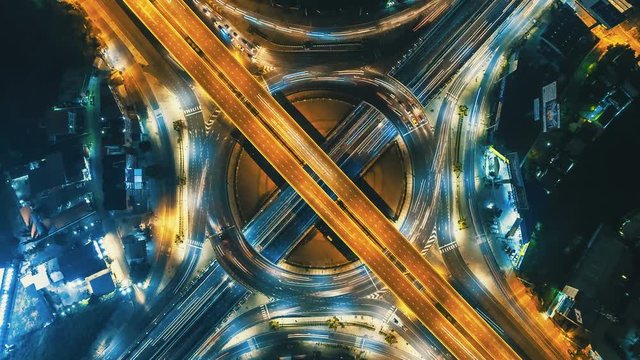 Hyperlapse timelapse zoom out of night city traffic on 4-way stop street intersection circle roundabout in bangkok, thailand. 4K UHD horizontal aerial view.