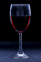 Low key glass of red wine with a dewdrop // still life