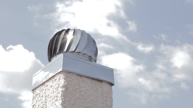 Turbine ventilator cap for chimney in a windy day with cloudy sky in the background. Wind protection chimney cap. 