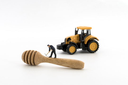 miniature worker working with spoon made of wood on white background.