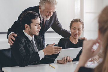 Marketing team consulting sales plan with supervisor senior manager in conference room before presenting to client.