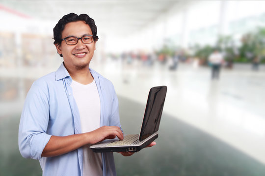 Young Man Smiling, Holding a Laptop