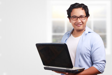 Young Man Smiling, Holding a Laptop