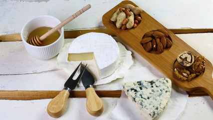 French camambert, cheese with blue mildew with honey and various types of nuts on the old table....