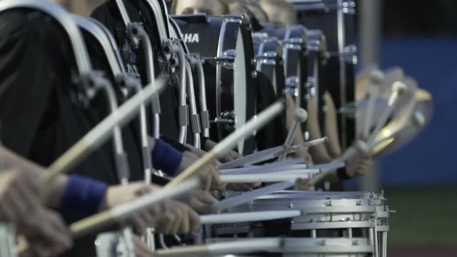 Marching band drummers with drumsticks in slow motion