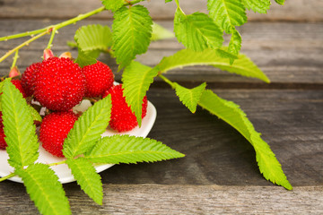 Red tibetan raspberry with leaves on wooden background with copy space