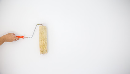 Painter's hand held roller to painting white color paints on the grey wall. image for add text,...