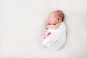 Fototapeten Cute newborn baby lies swaddled in a white blanket. Copy space and top view © irena_geo