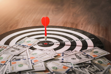 Red dart arrow hit the center target of dartboard and dollar metaphor marketing.