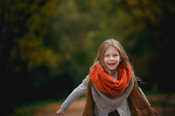 Positive little girl covered in plaid in the autumn park