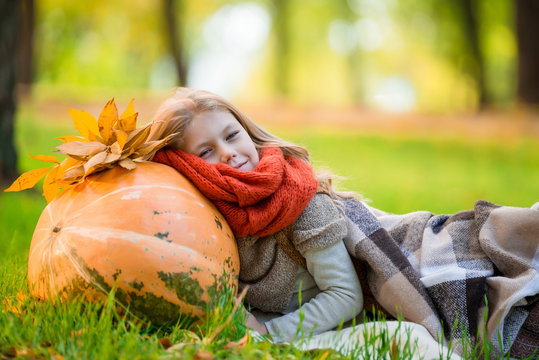Little girl with large pumpkin outdoor in autumn park
