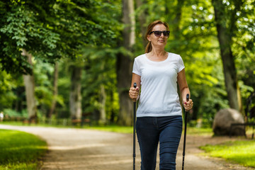 Nordic walking - middle-aged woman working out in city park