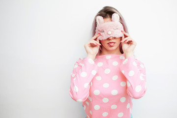 Beautiful young blonde in pink pajamas and a sleep mask on eyes