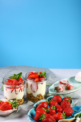 Fruit. Fresh red strawberries on old wooden background candy bar. Healthy layered dessert with cream, muesli isolated on a blue background. top view image with copy space