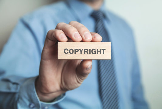 Businessman showing Copyright word in wooden block. Business concept