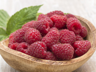 raspberry in a wooden plate on a kitchen table. 