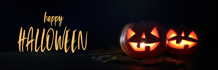Halloween holiday concept banner. Pumpkins over wooden table at night scary, haunted and misty forest.