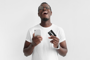 Transaction failed, declined. Young african american man holding credit card and smart phone in...