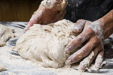 Male hands kneading dough on sprinkled