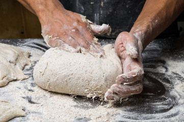 Male hands kneading dough on sprinkled