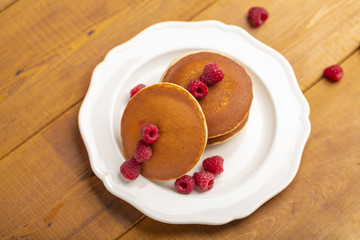  Small pancakes with raspberry and mint on wooden background