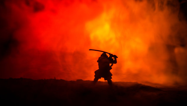 Fighter with a sword silhouette a sky ninja. Samurai on top of mountain with dark toned foggy background.