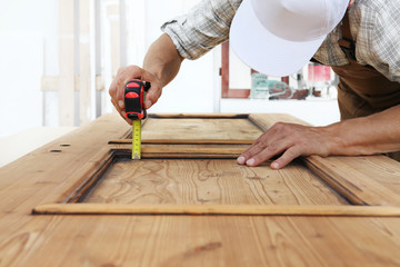 carpenter work the wood, measuring with meter tape a wooden vintage door